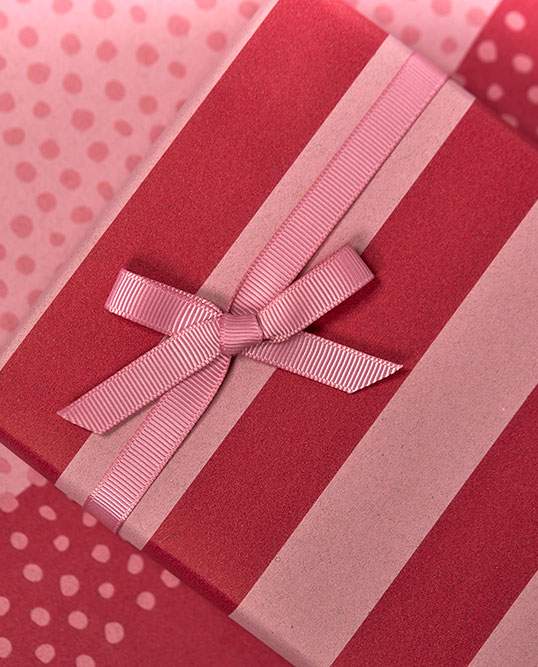 Rosa und rot gestreiftes Geschenkpapier mit rosa Schleife